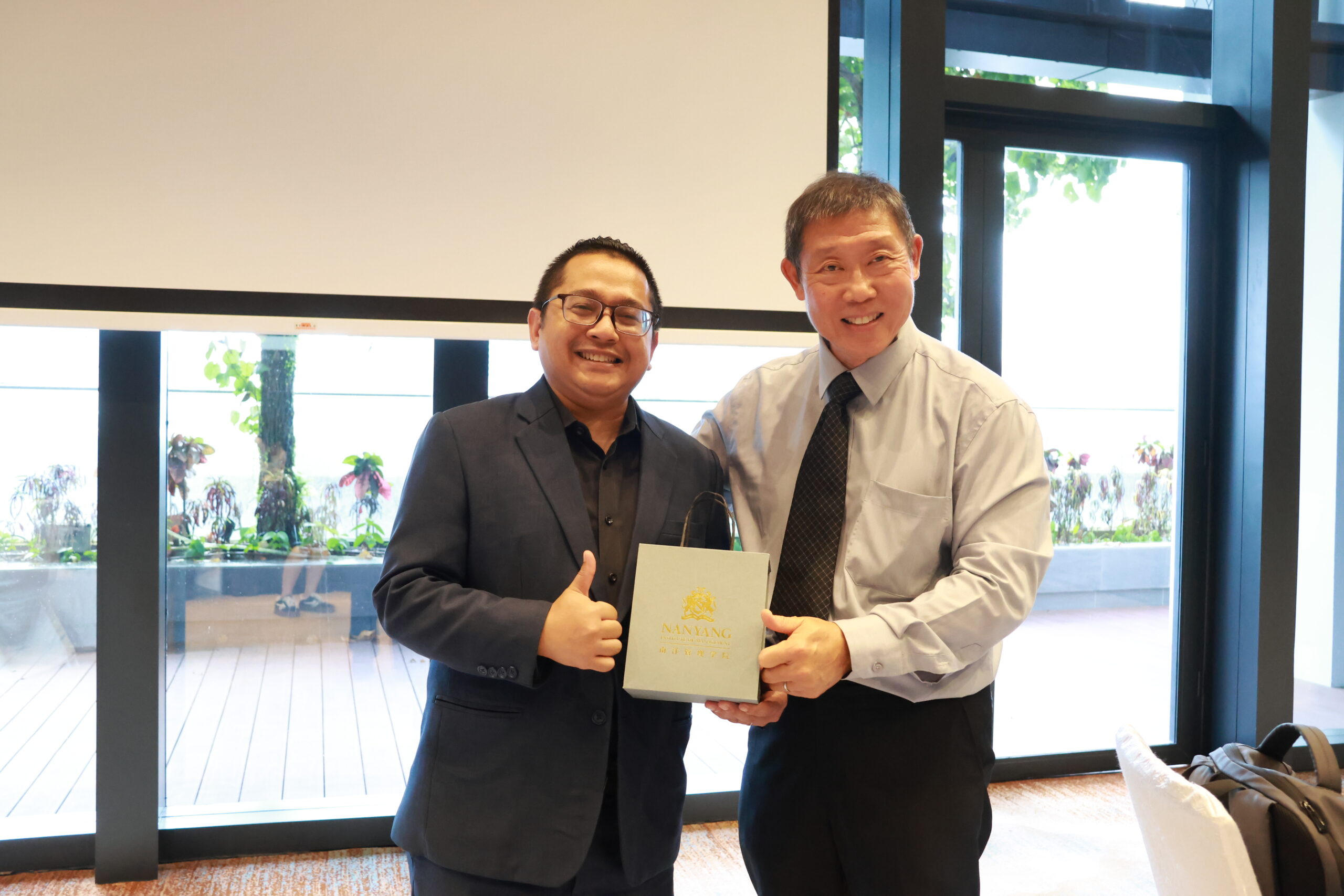 Nanyang Institute of Management's school of tourism and hospitality lecturer presenting a gratuitude award to Mr Fariz hakim from one farrer hotel